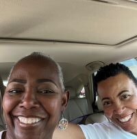 2 brown skinned women smile inside a car