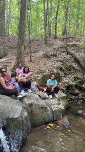 Five women sit on boulders with water running beneath them.