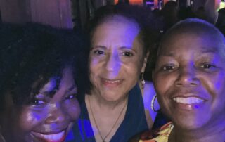 Three African-American women with radiant smiles.