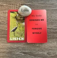 Two 3 x 5 red card with the word Love engraved on a rock between them. Card 1: text Listen with an image of a great blue heron on grass near water. Card 2: text: My body reminds me to forgive myself